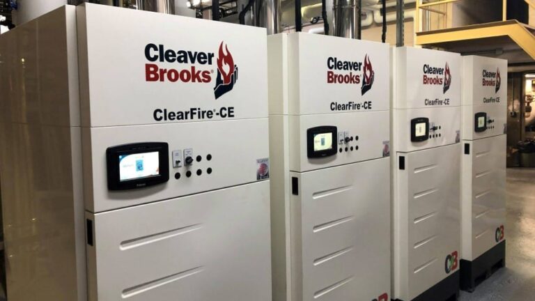 A row of Cleaver Brooks ClearFire-CE boilers, featuring a sleek white design with the company logo and product name prominently displayed. Each boiler unit is equipped with a digital control panel and various buttons for operation, situated in a clean industrial setting.